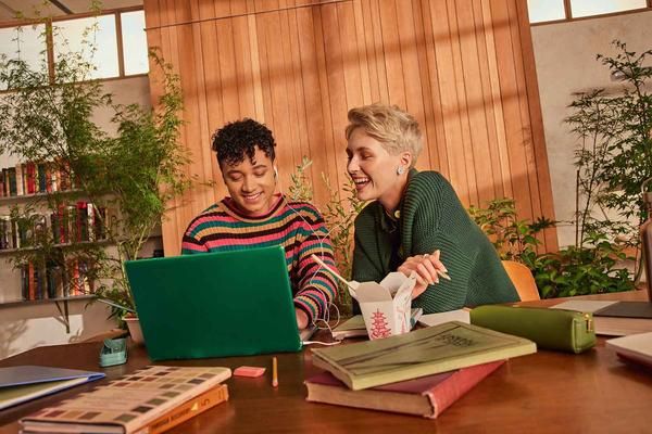 Father and daughter smiling while looking at a laptop screen.